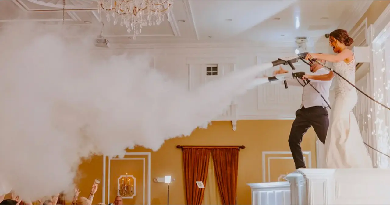 Two people fire CO2 cannons over a packed dance floor